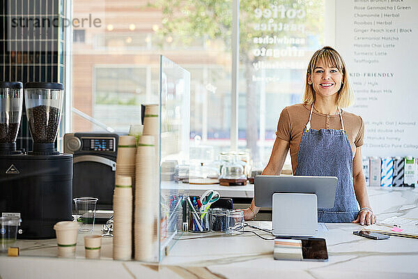 Lächelnde Kassiererin an der Kasse mit digitalem Tablet im Café