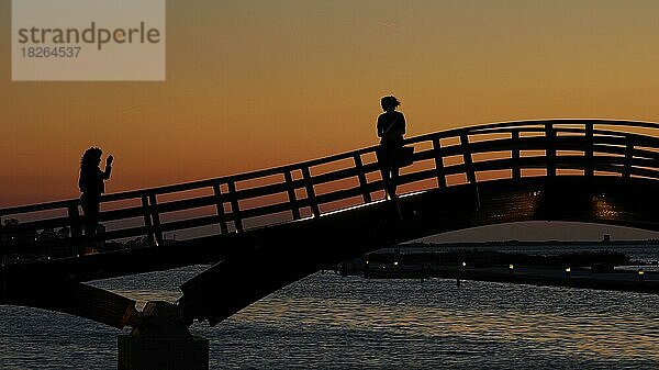 Abenddämmerung  Sonnenuntergang  Holzbrücke  Fußgängerbrücke über Kanal  Schattenriss  Fußgänger  eine Frau fotografiert andere Frau  Lefkada-Stadt  Hauptstadt  Insel Lefkada  Lefkas  Ionische Inseln  Griechenland  Europa