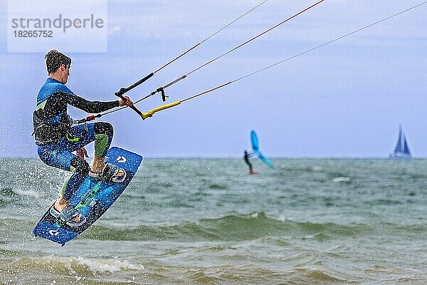 Kitesurfen mit Kiteboarder  Kitesurfer auf Twintip-Board beim Springen auf der Nordsee an einem windigen Tag