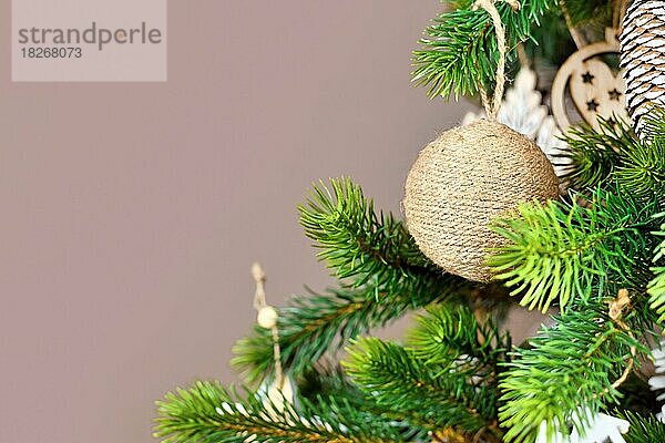 Weihnachtsbaumzweige mit natürlicher Christbaumkugel aus beigem Jutemantel mit Kopierraum