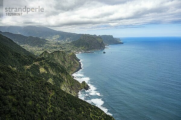 Ausblick auf steile bewaldete Küste und Meer  hinten Ort Porto da Cruz und Adlerfelsen Penha de Aguia  Küstenlandschaft  Wanderweg Vereda do Larano  Madeira  Portugal  Europa