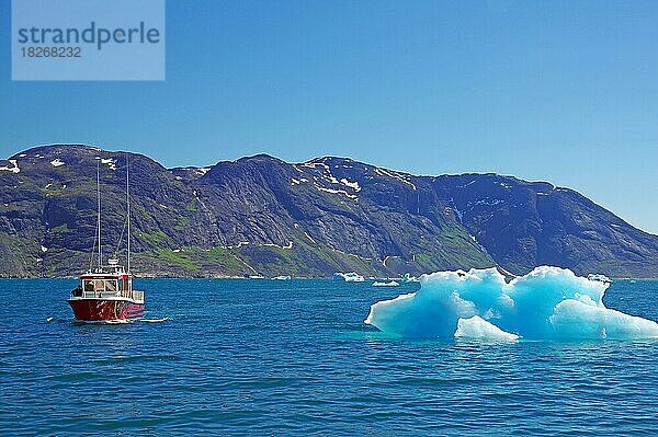 In der Sonne glitzerndes Eisstück neben einem kleinen Personenboot  Narsarsuaq  Grönland  Dänemark  Nordamerika