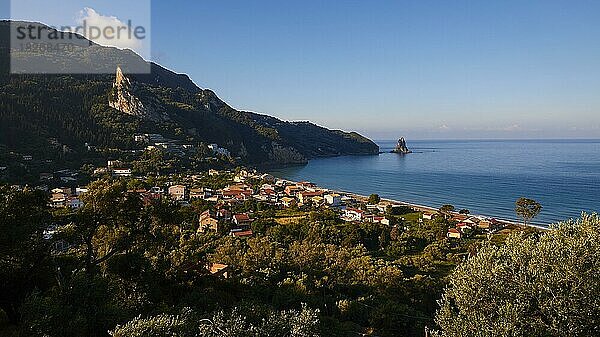 Agios Gordios  Bucht  Morgenlicht  Bäume  Häuser  Felsen im Meer  Otrholithos  blauer Himmel  wenige Wolken  blaues Meer  Insel Korfu  Ionische Inseln  Griechenland  Europa