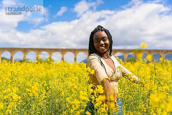 Lebensstil  Genießen der Natur in Freiheit  Porträt eines schwarzen ethnischen Mädchens mit Zöpfen  in einem Feld mit gelben Blumen