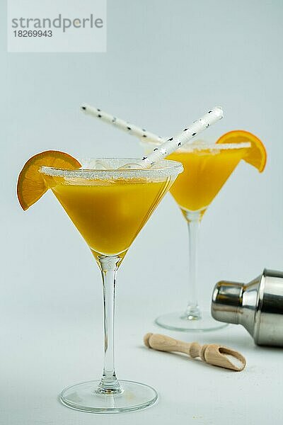 Frisch gepresster natürlicher Orangencocktail  in einem Glas mit einem Shaker am Boden