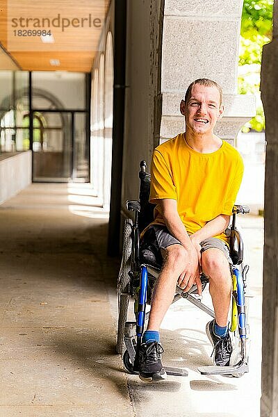 Porträt einer behinderten Person im Rollstuhl  die neben einigen Säulen in einer Tür lächelt