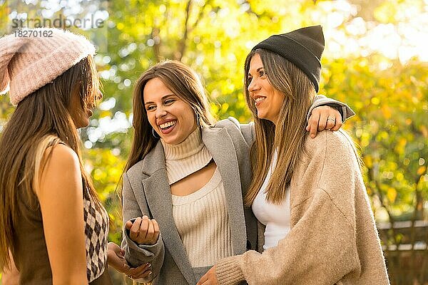 Lifestyle und herbstliches Outfit  Freundinnen haben Spaß in einem Park im Herbst bei Sonnenuntergang