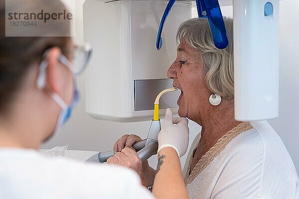 Zahnklinik  Zahnarzthelferin mit einer älteren Frau im Röntgenraum  die erklärt  wie sie die Stimme einsetzen müssen
