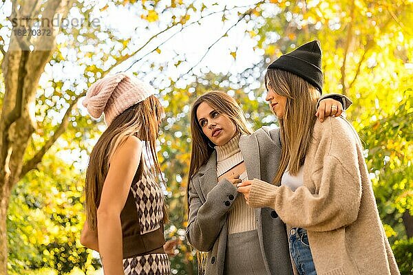 Freundinnen unterhalten sich in einem Park im Herbst bei Sonnenuntergang  Lifestyle und herbstliches Outfit