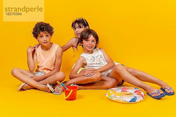 Kinder sitzen auf dem Boden und genießen die Sommerferien  gelber Hintergrund