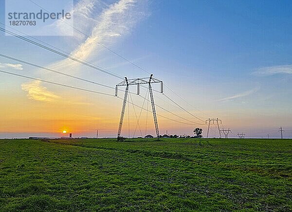 Hochspannungsmasten  ländliche Landschaft mit Strommasten in einer Reihe  bei Sonnenuntergang