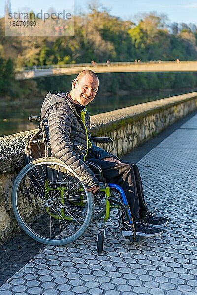 Porträt einer behinderten Person im Rollstuhl  die neben einem Fluss in einem Park lächelt