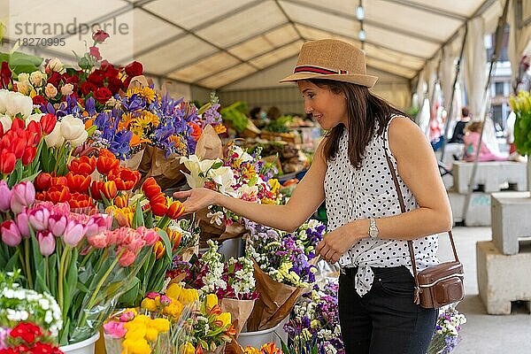 Eine hübsche Touristin mit einer Fotokamera  die einen Blumenmarkt besucht und den Frühling oder Sommerurlaub genießt