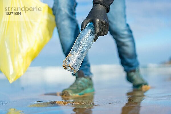 Meeresverschmutzung  nicht erkennbare Person  die am Strand Müll und Plastik sammelt. Ökologiekonzept