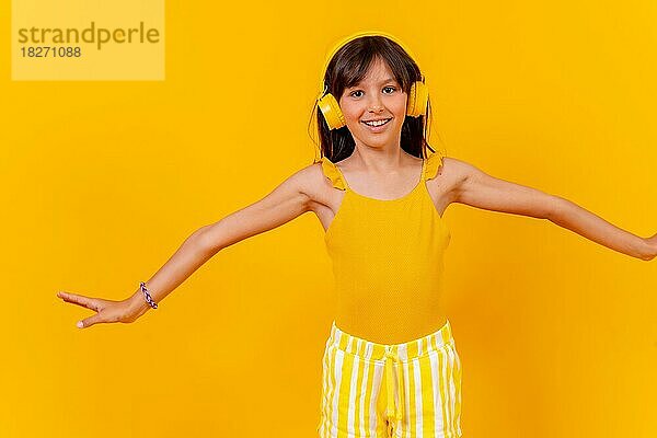 Ein Mädchen hört Musik und tanzt mit drahtlosen Kopfhörern  gelber Hintergrund