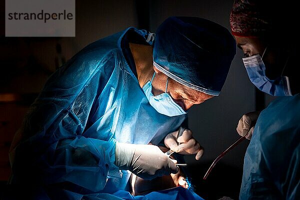 Zahnklinik  Zahnarzt und Assistentin führen eine orale Operation bei schwachem Licht durch