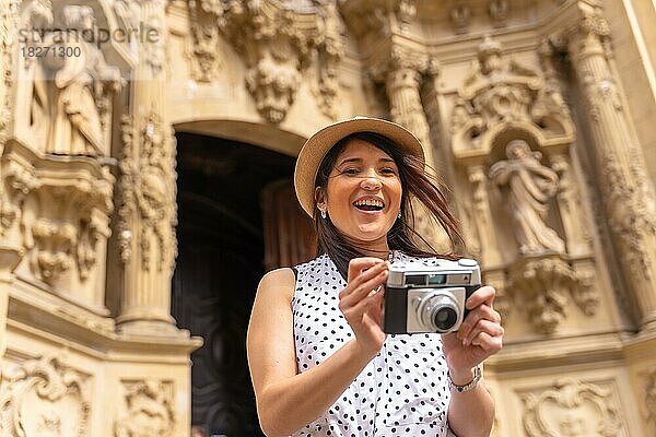 Lächelnde Touristin mit Hut  die eine Kirche besucht und Fotos mit einer Kamera macht  Sommerurlaub genießt  Konzept der weiblichen Reisenden und der Schöpferin digitaler Inhalte