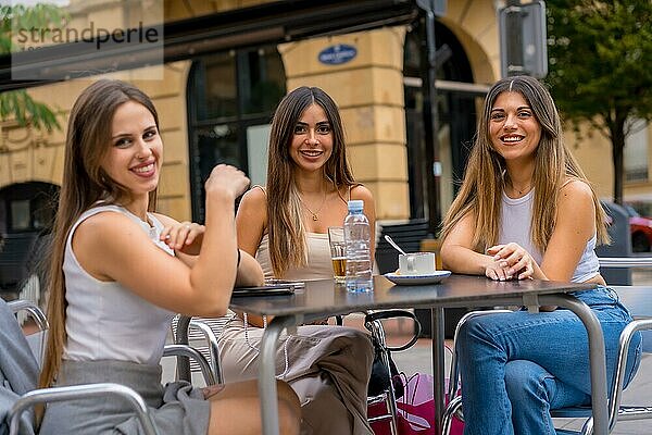 Porträt von jungen Freundinnen  die an einem Nachmittag auf der Terrasse einer Cafeteria etwas trinken