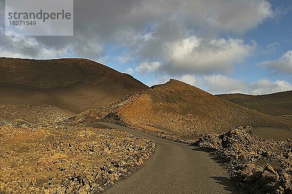 Asphaltierte Straße im Nationalpark  rotbraune Lava-Landschaft  Timanfaya-Nationalpark  Feuerberge  Vulkanlandschaft  blauer Himmel  grauweiße Wolken  Lanzarote  Kanarische Inseln  Spanien  Europa