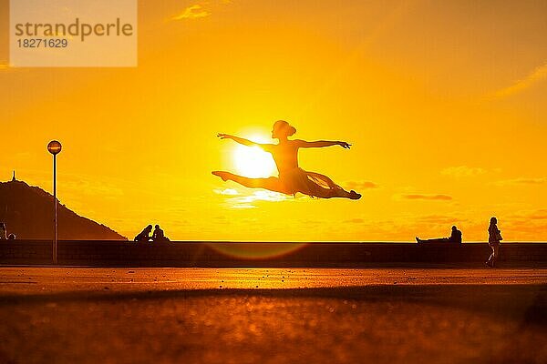 Silhouette einer jungen Tänzerin bei einem Sprung am Strand bei Sonnenuntergang