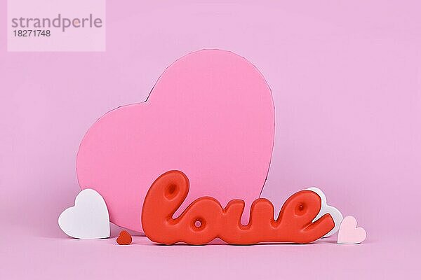 Valentinstag Dekoration mit roten Wort Liebe  Geschenk-Box und Herz-Ornamente auf rosa Hintergrund