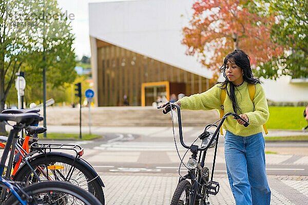 Junge asiatische Studentin parkt das Fahrrad auf dem Universitätscampus  gesundes und grünes Leben