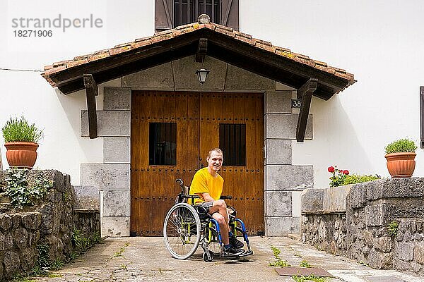 Porträt einer behinderten Person im Rollstuhl im Eingang ihres Hauses  die lächelt