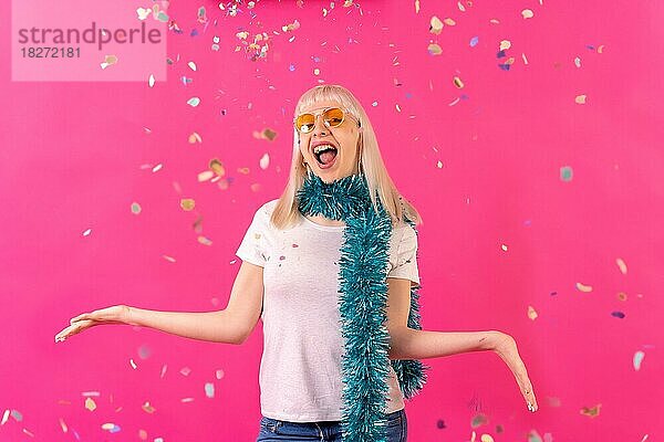 Sehr glücklich und lächelnd auf Konfetti Party trägt Sonnenbrille  blonde kaukasische Mädchen auf rosa Hintergrund Studio