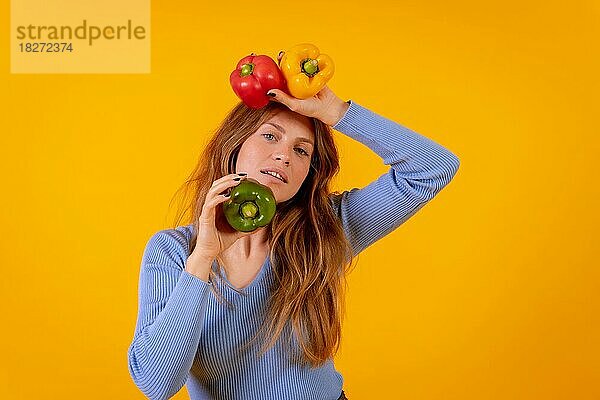 Vegane Frau mit grünen  gelben und roten Paprikaschoten auf gelbem Hintergrund  vegetarisches Leben