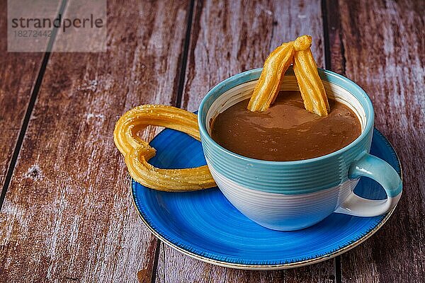 Heiße Schokolade mit einem Churro in Form eines Herzens auf einem Holztisch