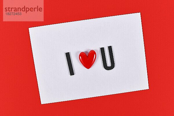Valentinstag Text Ich liebe dich buchstabiert mit Herz auf weißer Karte auf rotem Hintergrund