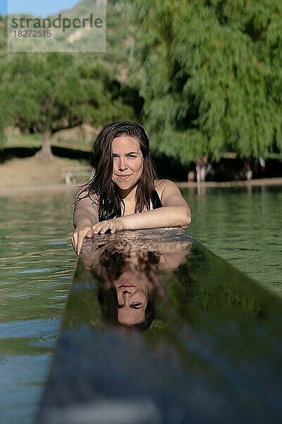 Attraktives junges Mädchen spiegelt sich im Wasser eines Sees