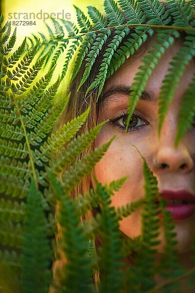 Blick einer jungen brünetten Frau in der Natur in einem Naturpark unter Farnblättern