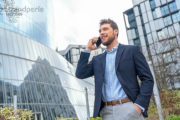 Männlicher Geschäftsmann oder Unternehmer im Gespräch am Telefon außerhalb des Büros  Gewerbegebiet