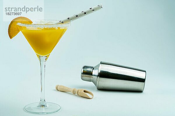 Frisch gepresster natürlicher Orangencocktail  in einem Glas mit einem Shaker am Boden