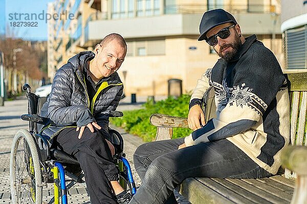 Porträt einer behinderten Person im Rollstuhl mit einem Freund  der sich auf der Straße amüsiert