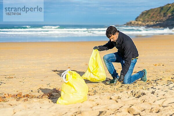 Freiwillige Person sammelt Plastik aus dem Sand am Strand. Ökologiekonzept  Meeresverschmutzung