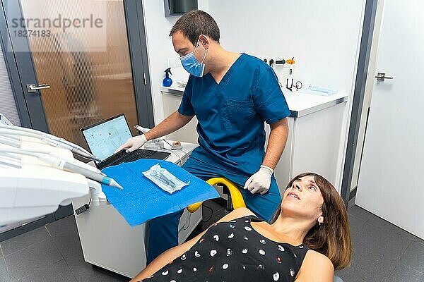 Zahnklinik  Zahnarzt schaut sich die Prothese eines jungen Patienten an
