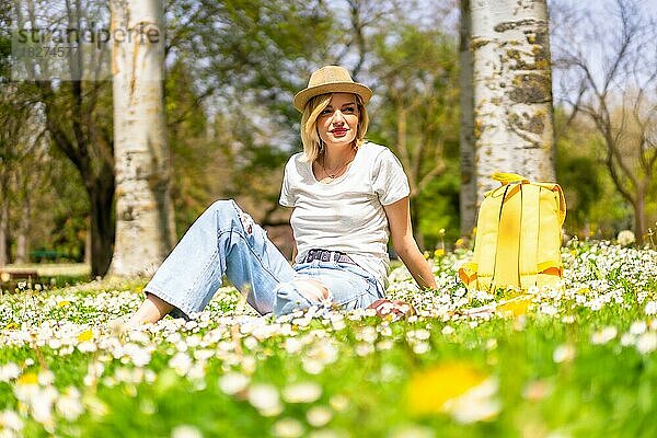 Ein junges blondes Mädchen genießt den Frühling in einem Park in der Stadt  Urlaub in der Natur und neben Gänseblümchen