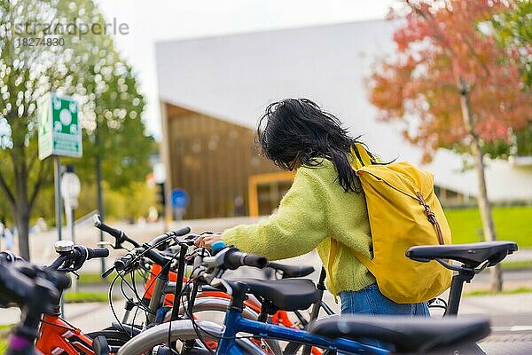Asiatische Studentin beim Parken des Fahrrads auf dem College-Campus  gesundes und grünes Leben