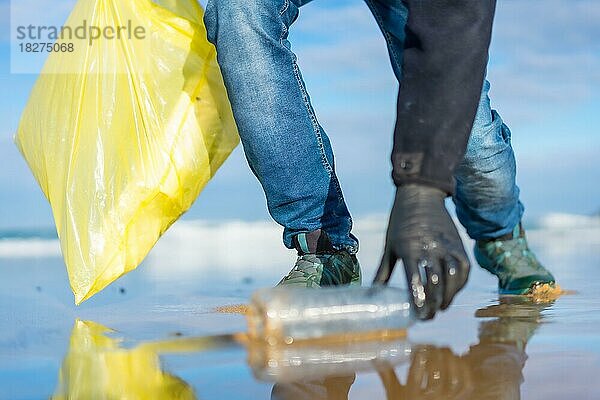 Meeresverschmutzung  nicht erkennbare Person  die am Strand Müll und Plastik sammelt. Ökologiekonzept