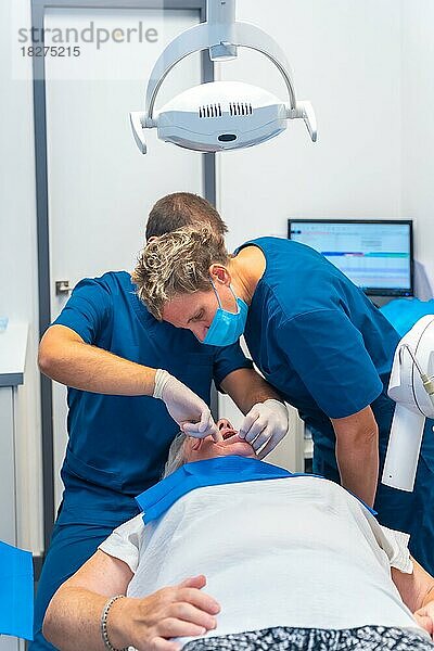Zahnklinik  Zahnarzt und Assistentin bei der Untersuchung der Zähne einer älteren Frau