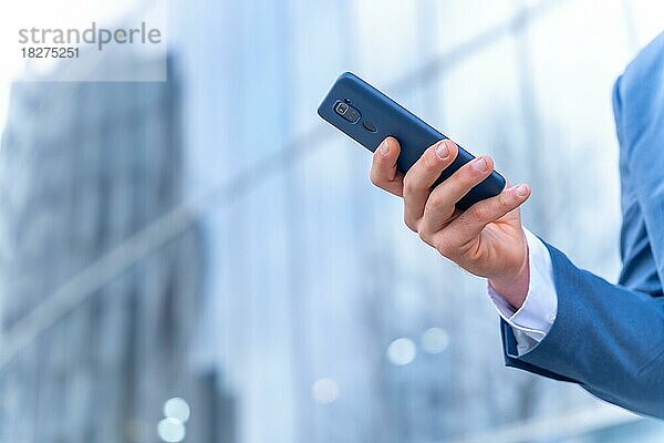 Unbekannte Person  Geschäftsmann vor dem Büro in einem Glasgebäude  mit einem Telefon