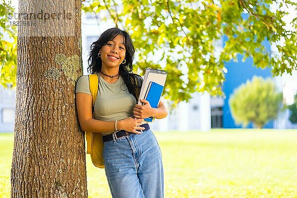Asiatisches Mädchen auf dem Campus  lächelnd im College unter einem Baum