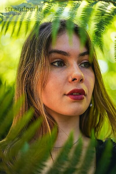 Porträt einer jungen brünetten Frau in der Natur in einem Naturpark unter Farnblättern