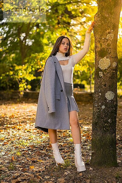 Porträt einer hübschen Frau  die den Herbst in einem Park bei Sonnenuntergang genießt  herbstliches Outfit