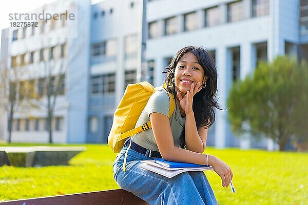 Asiatisches Mädchen auf dem Campus  Studentin  die den Unterricht genießt  lächelnd an der Universität  sitzend