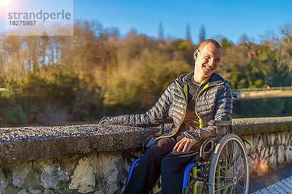 Eine behinderte Person im Rollstuhl in einem Park bei Sonnenuntergang lächelnd