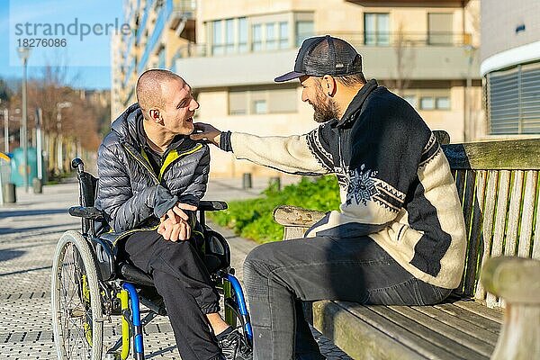 Behinderte Person im Rollstuhl mit einem Freund  der sich amüsiert und unterhält