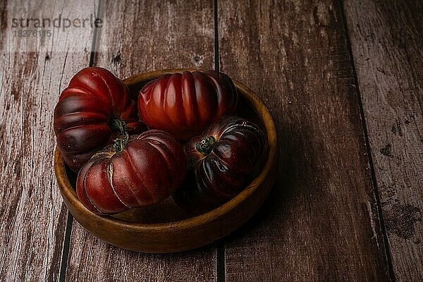Gruppe von maurischen Tomaten in einer Holzschale vor einem Holztisch